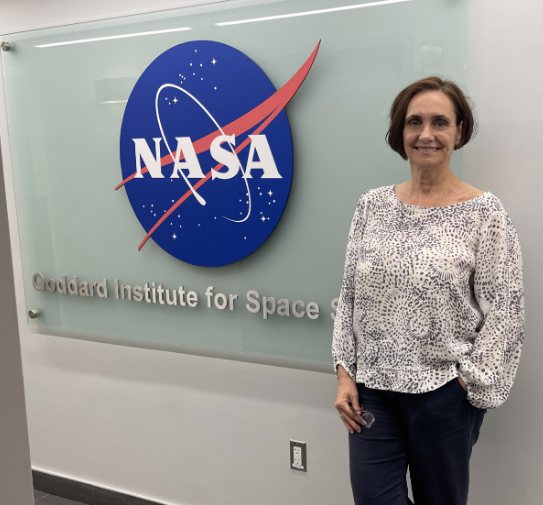 Anastasia Romanou stands beside a wall-mounted NASA logo above the words Goddard Institute for Space Studies