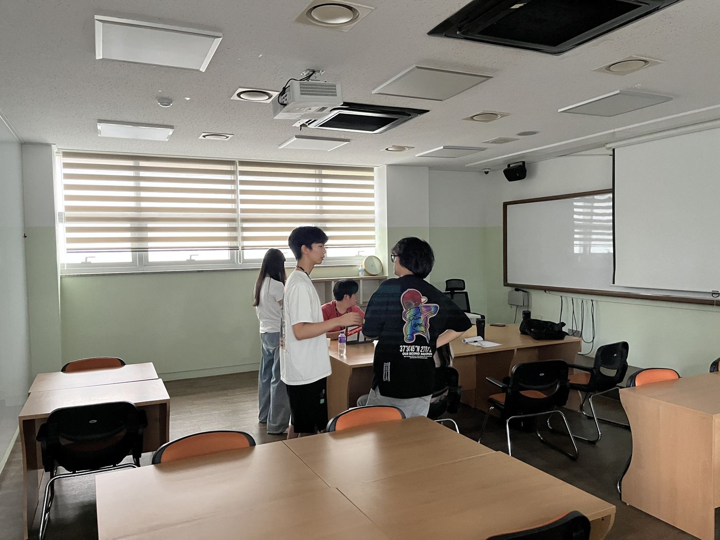 Students standing around a desk as a teammate works on a laptop in an SRP classroom