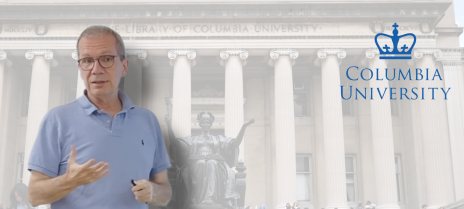 George Tselioudis gestures as he speaks, set against the columns of a Columbia University library building and the university's crown logo